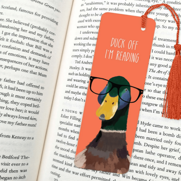 Card Duck Bookmark with Orange Tassel placed on a page inside a book